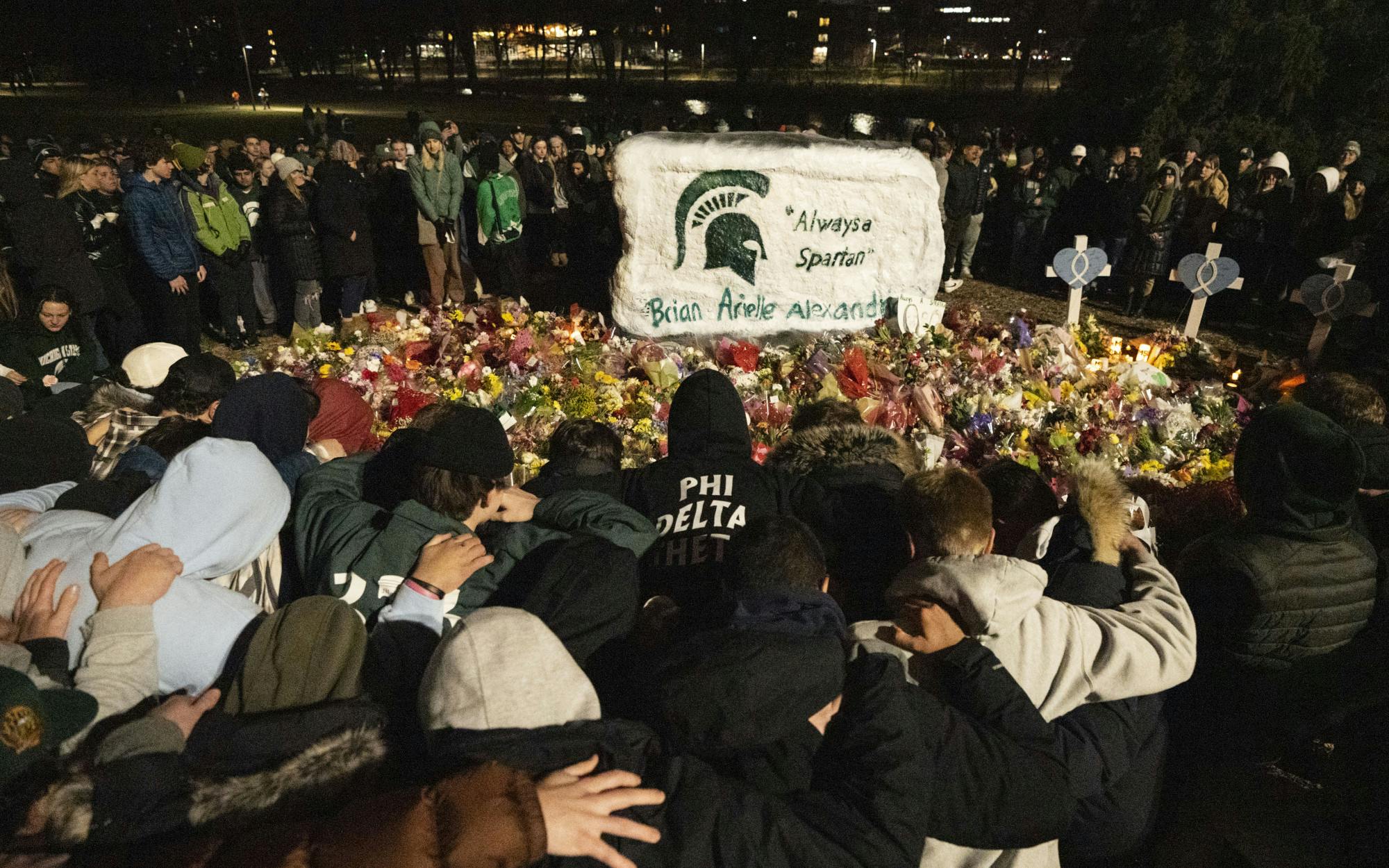 <p>Brian Fraser’s Phi Delta Theta brothers kneeled in front of the memorial made for him, Alexandria Verner and Arielle Anderson, during the vigil on Wednesday, Feb. 15, 2023. Thousands gathered at the Rock on Farm Lane to honor the three victims of, and the five hospitalized by, Michigan State University’s mass shooting on Feb. 13.</p>